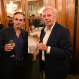 Alain Marty, à droite, avec un verre à la main, discute avec un homme à lunettes.