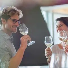 Un homme et une femme dégustent du vin blanc, un moment convivial pour ce guide du vin.