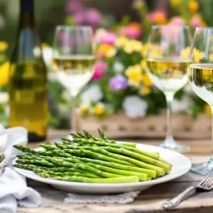 Un plateau d'asperges vertes fraîches, prêt à être dégusté avec du vin blanc. Idéal pour savoir avec quoi associer les asperges lors d'un repas printanier.