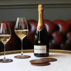 Bouteille de champagne Bollinger Special Cuvée et deux verres remplis, sur un plateau en marbre. Un avis sur ce champagne ? Il est excellent !