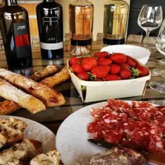 Dégustation à la cave la romaine : vins, charcuterie, fraises et pains croustillants sur une table en bois.