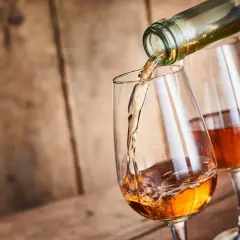 Un verre se remplit d'un vin paillé ambré, un autre verre déjà plein est à côté.