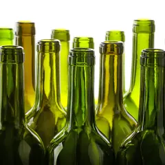 Une rangée de bouteilles de vin vertes vides, posées côte à côte. Le verre vert protège le vin, expliquant pourquoi les bouteilles de vin sont vertes.