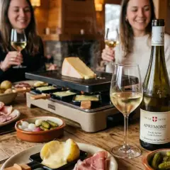 Un groupe d'amis savoure une raclette et du vin blanc, avec une bouteille d'Apremont. Le pinot noir raclette est un délice.