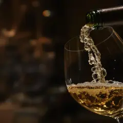 Un vin nature coule d'une bouteille dans un verre, créant une mousse légère. Une invitation à découvrir l'authenticité.