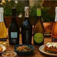 Cinq bouteilles de vin pétillant, dont un Riondo Prosecco, sont disposées sur une table en bois avec des plats de fruits de mer et un poulet rôti.