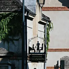 Panneau "Domaine Chanson" avec silhouettes de personnes attablées, devant un bâtiment couvert de végétation.