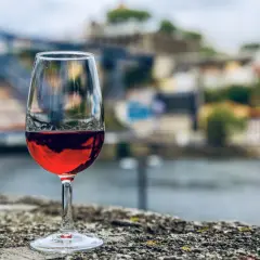 Verre de vin rouge sur un muret, avec la ville de Porto et le fleuve en arrière-plan. Une belle dégustation vin porto.