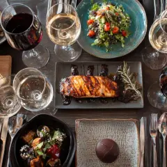 Une table dressée avec des plats variés et des verres de vin rouge et blanc. Une invitation à découvrir la fiche technique accord mets et vins.