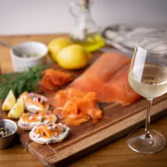 Un verre de vin blanc, parfait pour accompagner du saumon fumé, des toasts au fromage frais, câpres et oignons rouges.