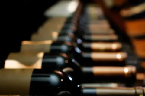 Des bouteilles de vin alignées, évoquant les meilleurs vins du Roussillon, dans une cave sombre.