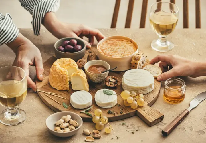 Un plateau de fromages variés, dont un fromage de chèvre du **Pays de la Loire**, accompagné de raisins, olives, pistaches et miel.