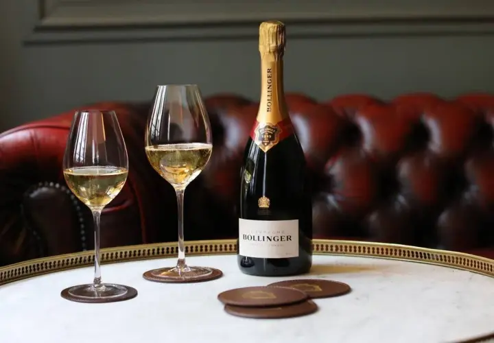 Bouteille de champagne Bollinger Special Cuvée et deux verres remplis, sur un plateau en marbre. Un avis sur ce champagne ? Il est excellent !