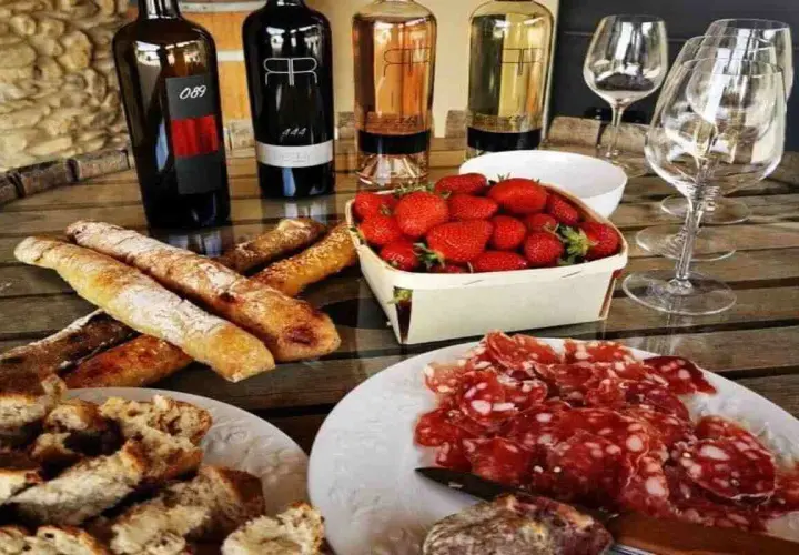 Dégustation à la cave la romaine : vins, charcuterie, fraises et pains croustillants sur une table en bois.