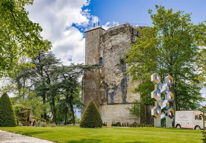 La tour des fiefs Sancerre, vestige historique, se dresse fièrement dans un parc verdoyant, orné d'une sculpture moderne et d'un food truck.