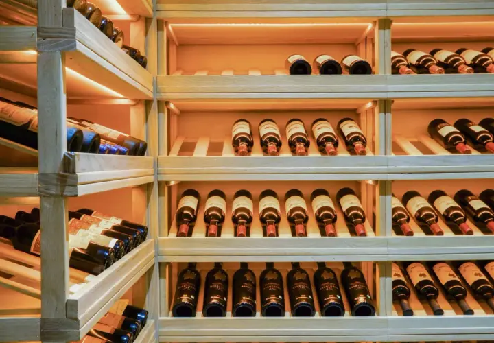 Une cave à vin en bois avec de nombreuses bouteilles. Un guide millésime vin idéal pour choisir la meilleure cuvée.