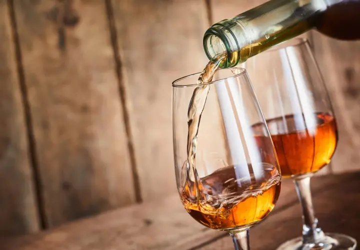 Un verre se remplit d'un vin paillé ambré, un autre verre déjà plein est à côté.