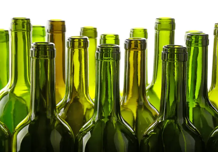 Une rangée de bouteilles de vin vertes vides, posées côte à côte. Le verre vert protège le vin, expliquant pourquoi les bouteilles de vin sont vertes.