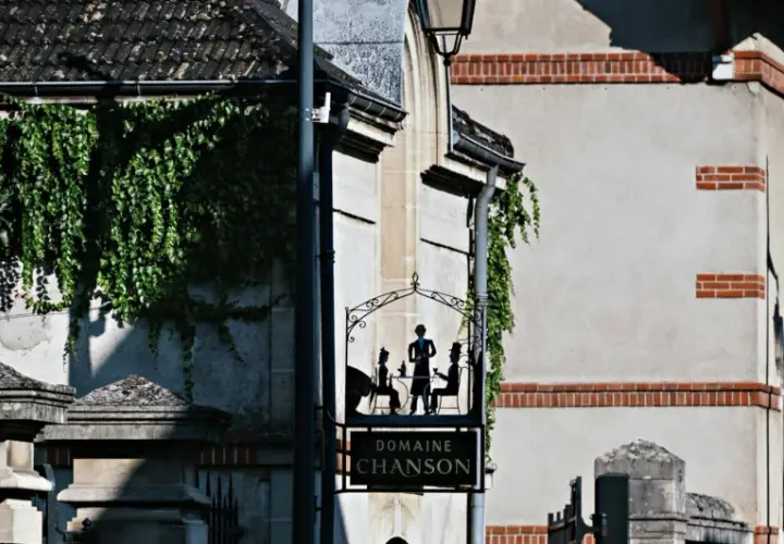 Panneau "Domaine Chanson" avec silhouettes de personnes attablées, devant un bâtiment couvert de végétation.