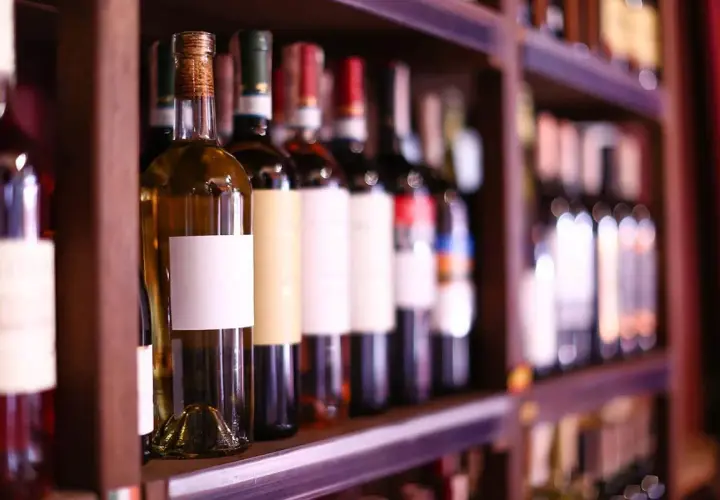 Étagères remplies de bouteilles de vin, certaines avec des étiquettes blanches vierges, prêtes à accueillir le meilleur cépage de vin rouge.