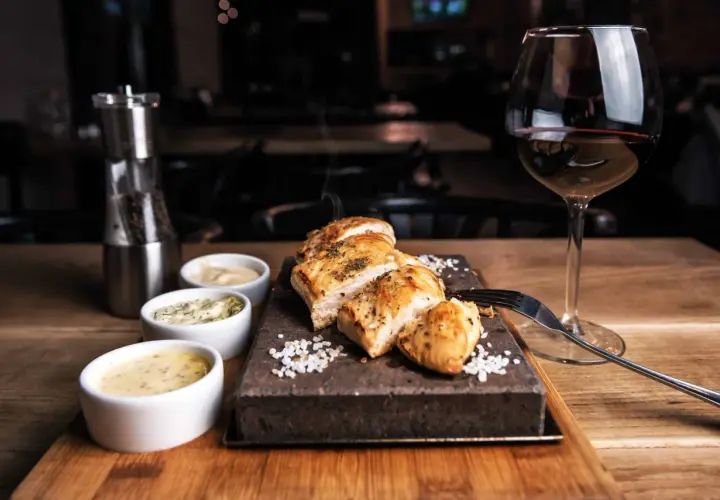 Un plat de viande blanche savoureux, servi avec trois sauces et un verre de vin rouge. Le choix parfait pour savoir quel vin avec viande blanche.