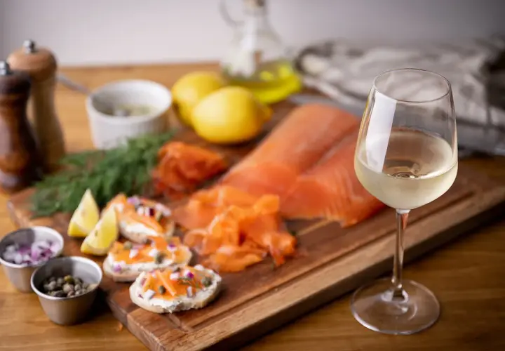 Un verre de vin blanc, parfait pour accompagner du saumon fumé, des toasts au fromage frais, câpres et oignons rouges.