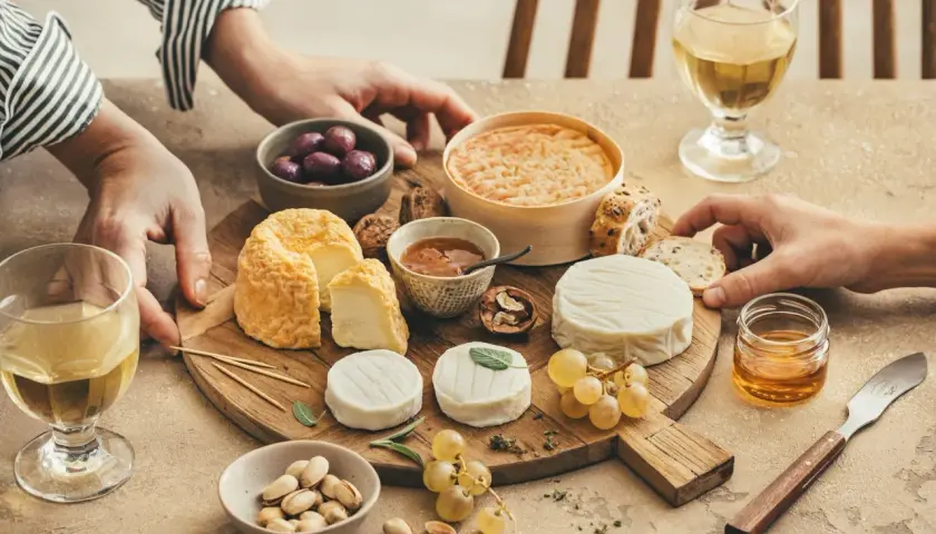 Un plateau de fromages variés, dont un fromage de chèvre du **Pays de la Loire**, accompagné de raisins, olives, pistaches et miel.