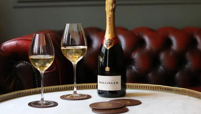 Bouteille de champagne Bollinger Special Cuvée et deux verres remplis, sur un plateau en marbre. Un avis sur ce champagne ? Il est excellent !