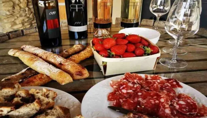Dégustation à la cave la romaine : vins, charcuterie, fraises et pains croustillants sur une table en bois.