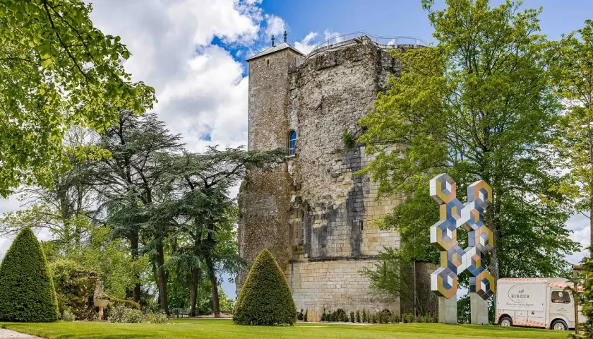 La tour des fiefs Sancerre, vestige historique, se dresse fièrement dans un parc verdoyant, orné d'une sculpture moderne et d'un food truck.