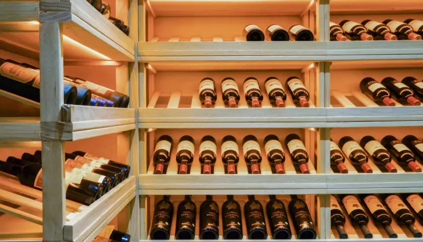 Une cave à vin en bois avec de nombreuses bouteilles. Un guide millésime vin idéal pour choisir la meilleure cuvée.