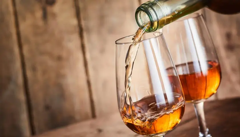Un verre se remplit d'un vin paillé ambré, un autre verre déjà plein est à côté.