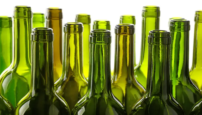 Une rangée de bouteilles de vin vertes vides, posées côte à côte. Le verre vert protège le vin, expliquant pourquoi les bouteilles de vin sont vertes.