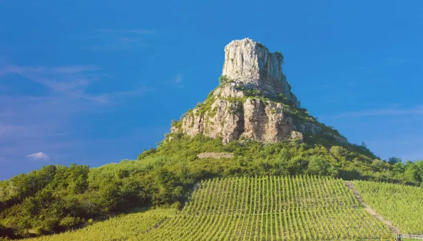 Le rocher de la Roche de Solutré, site emblématique de la Bourgogne, se dresse fièrement au-dessus des vignobles verdoyants. Un paysage à couper le souffle, digne des plus belles cartes postales de guffens heynen.