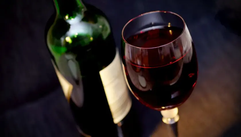 Bouteille de vin rouge et verre rempli. Attention, un vin trop vieux peut présenter un danger.