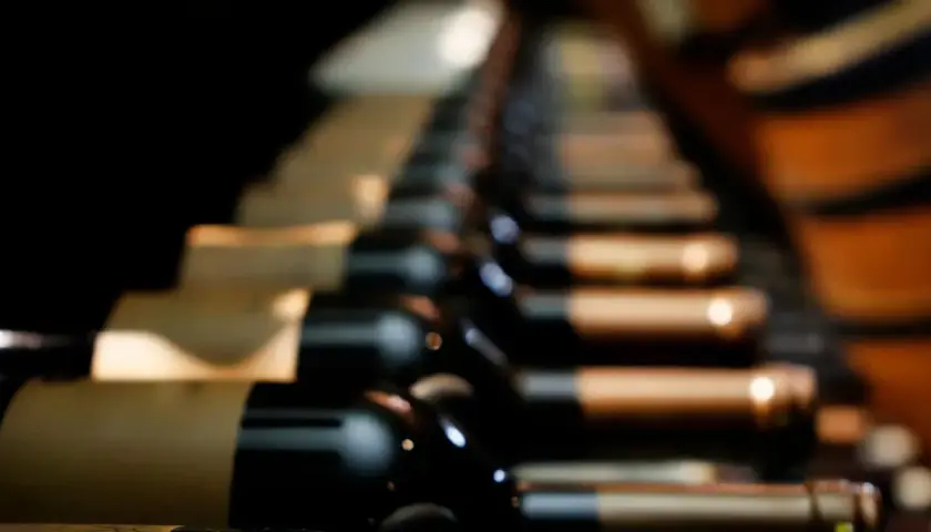 Des bouteilles de vin alignées, évoquant les meilleurs vins du Roussillon, dans une cave sombre.