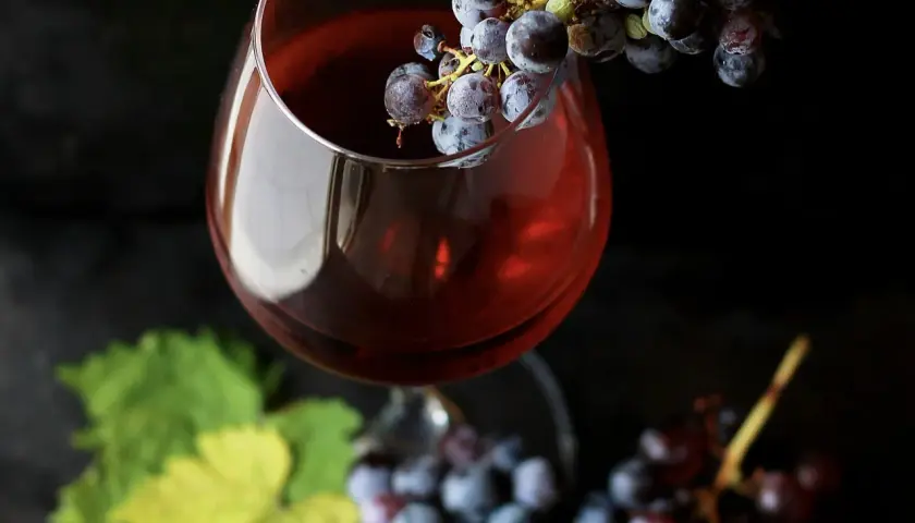 Verre de vin rouge avec des grappes de raisin, évoquant la conservation du beaujolais nouveau.
