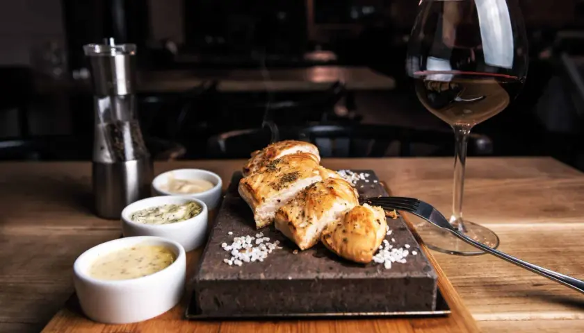 Un plat de viande blanche savoureux, servi avec trois sauces et un verre de vin rouge. Le choix parfait pour savoir quel vin avec viande blanche.