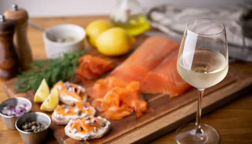 Un verre de vin blanc, parfait pour accompagner du saumon fumé, des toasts au fromage frais, câpres et oignons rouges.