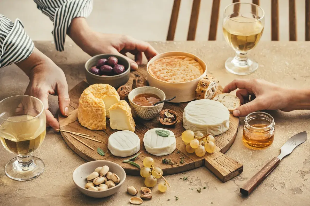 Un plateau de fromages variés, dont un fromage de chèvre du **Pays de la Loire**, accompagné de raisins, olives, pistaches et miel.