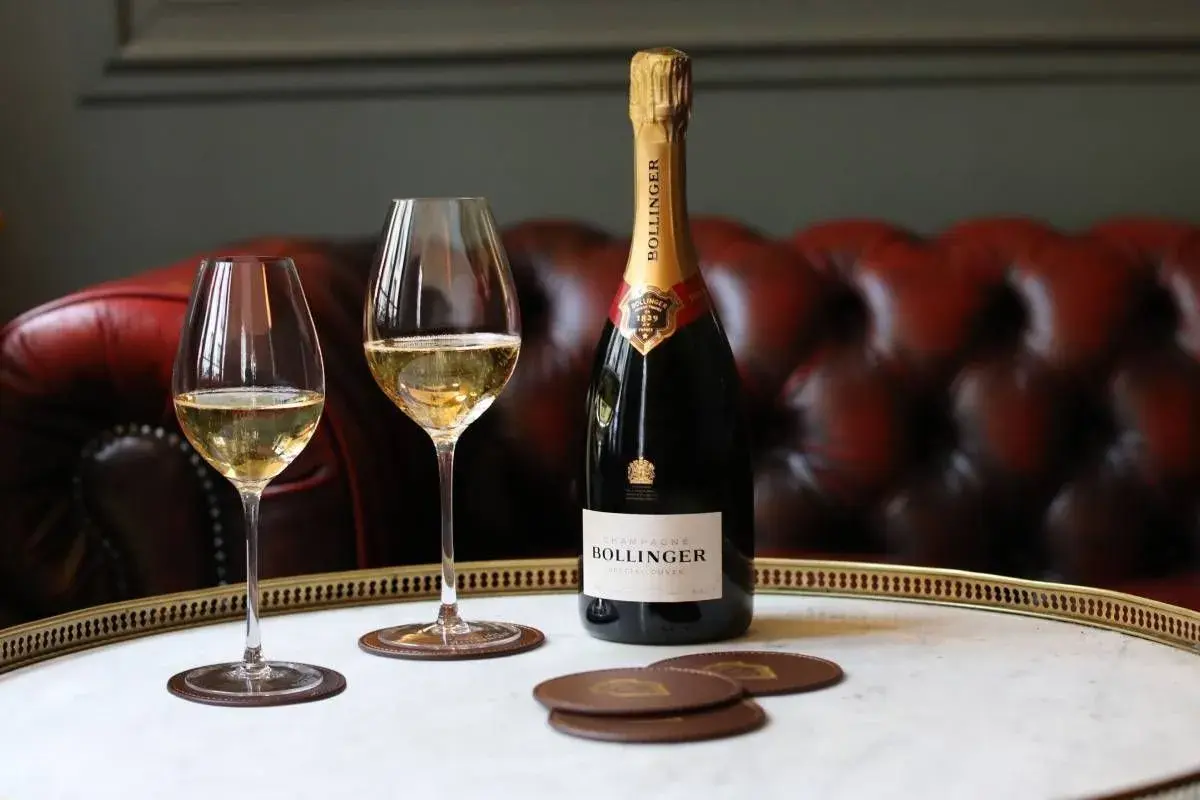 Bouteille de champagne Bollinger Special Cuvée et deux verres remplis, sur un plateau en marbre. Un avis sur ce champagne ? Il est excellent !