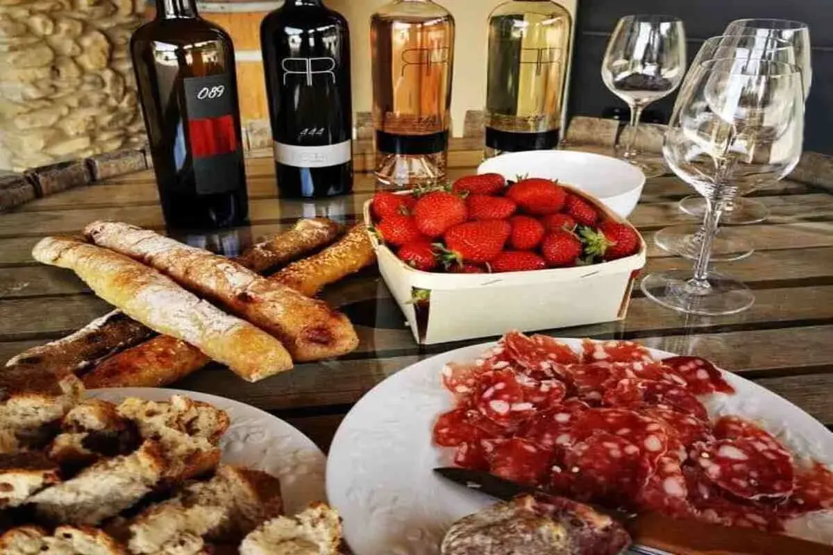 Dégustation à la cave la romaine : vins, charcuterie, fraises et pains croustillants sur une table en bois.