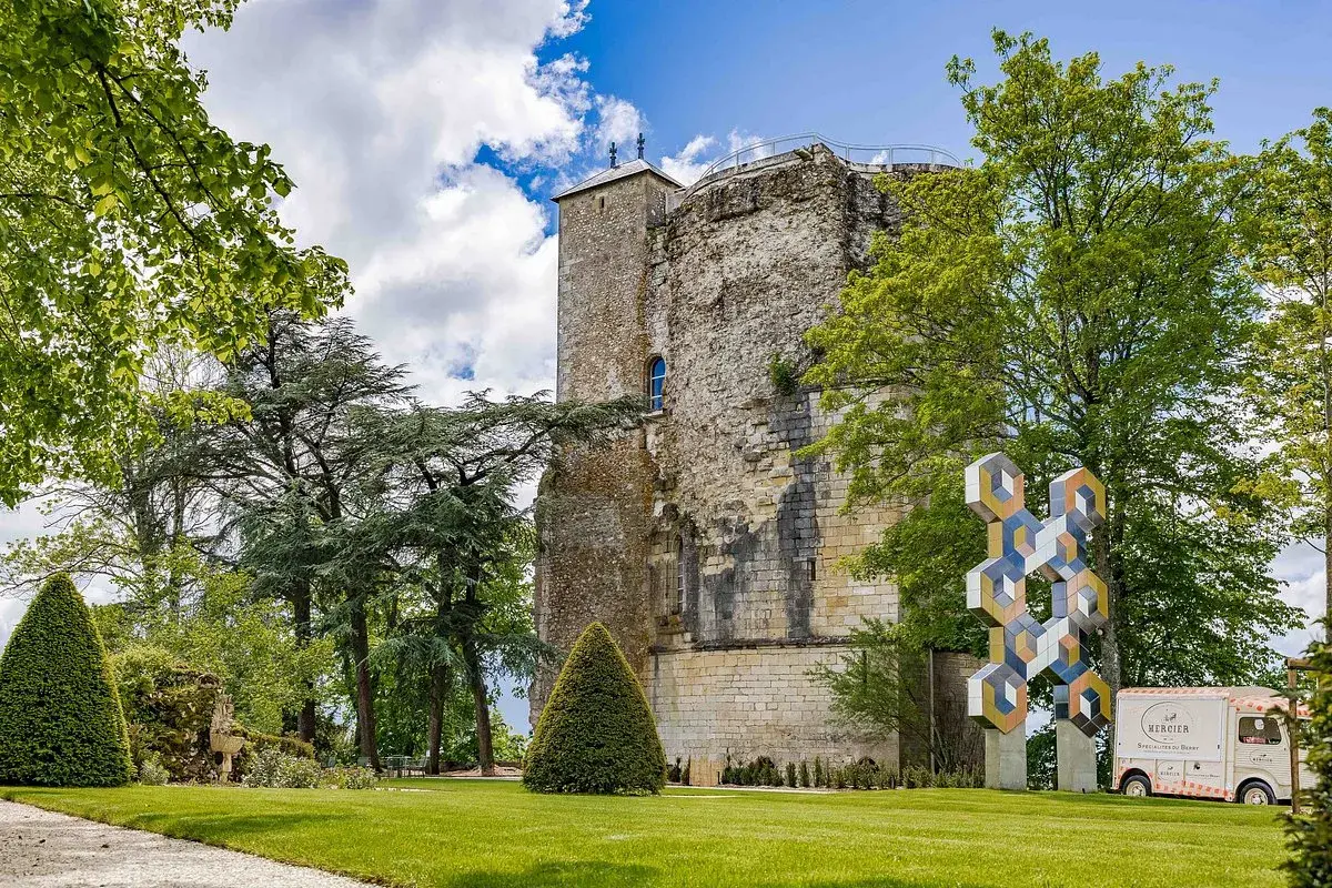 La tour des fiefs Sancerre, vestige historique, se dresse fièrement dans un parc verdoyant, orné d'une sculpture moderne et d'un food truck.