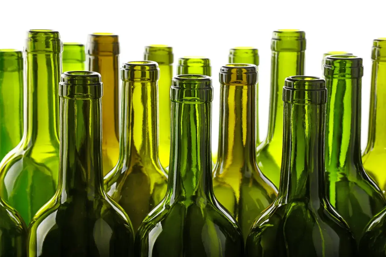 Une rangée de bouteilles de vin vertes vides, posées côte à côte. Le verre vert protège le vin, expliquant pourquoi les bouteilles de vin sont vertes.