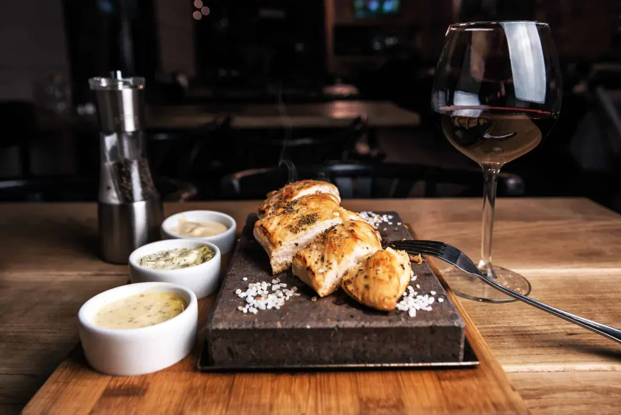 Un plat de viande blanche savoureux, servi avec trois sauces et un verre de vin rouge. Le choix parfait pour savoir quel vin avec viande blanche.