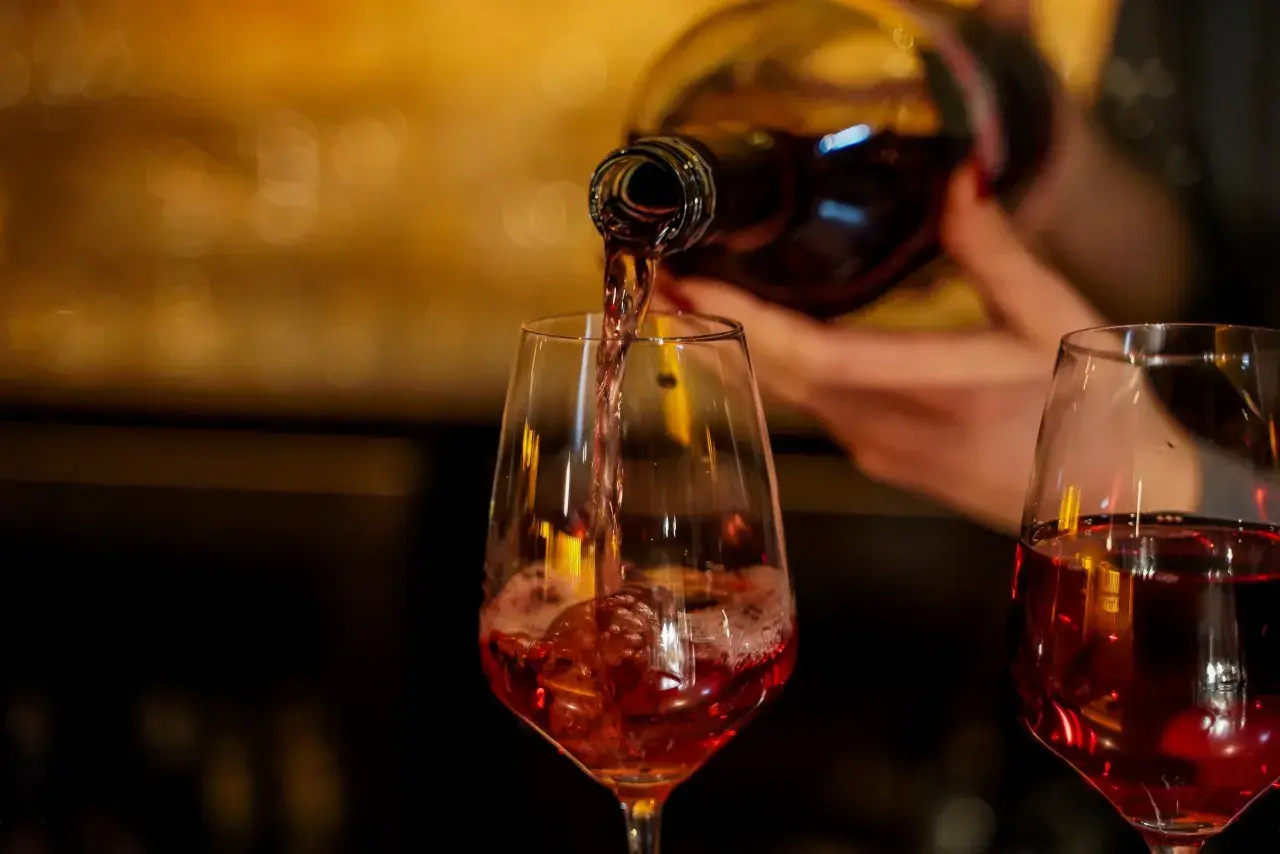 Verre de beaujolais nouveau rempli, avec une bouteille en arrière-plan.