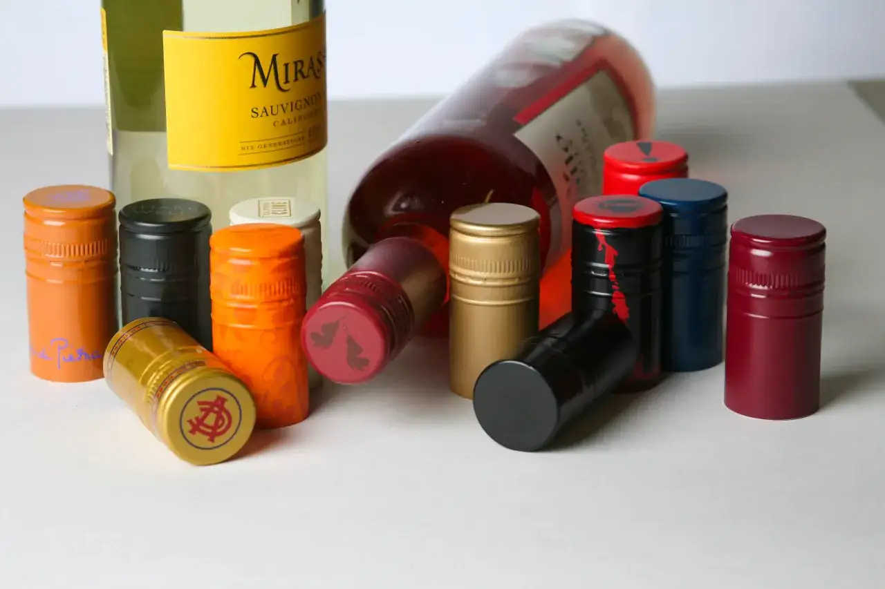 Un assortiment de capsules de vin aux couleurs vives : orange, noir, or, rouge, bleu et bordeaux. Chaque couleur capsule vin &eacute;voque une ambiance diff&eacute;rente.