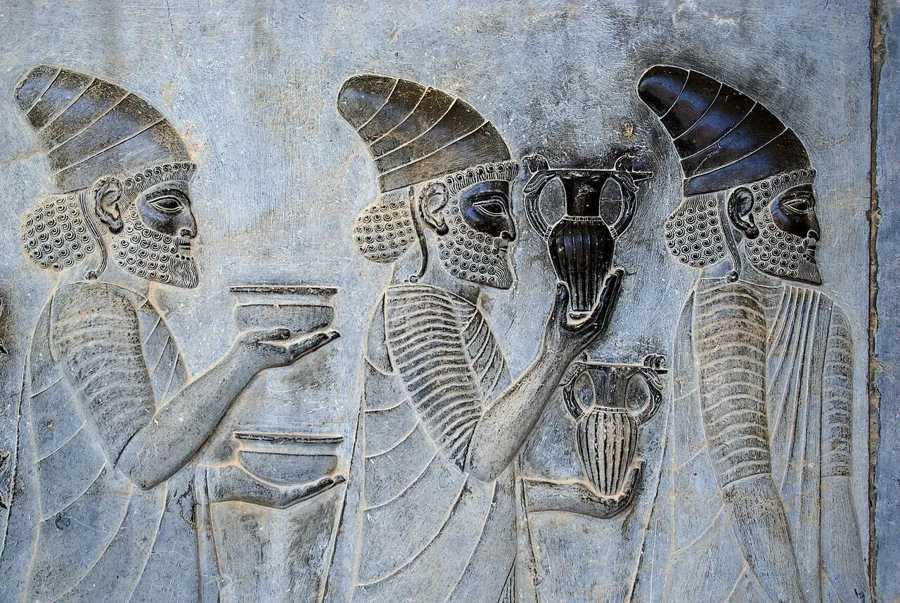 Bas-relief persan : des hommes portant des vases, peut-être des offrandes ou des récipients pour le vin, témoignant de l'ancien berceau du vin.