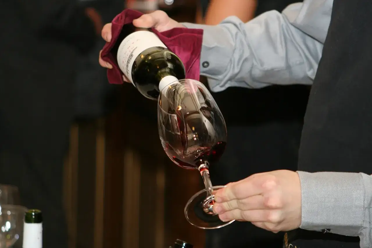 Un sommelier verse du vin rouge dans un verre, r&eacute;v&eacute;lant la richesse et la complexit&eacute; de ce que contient le vin rouge.