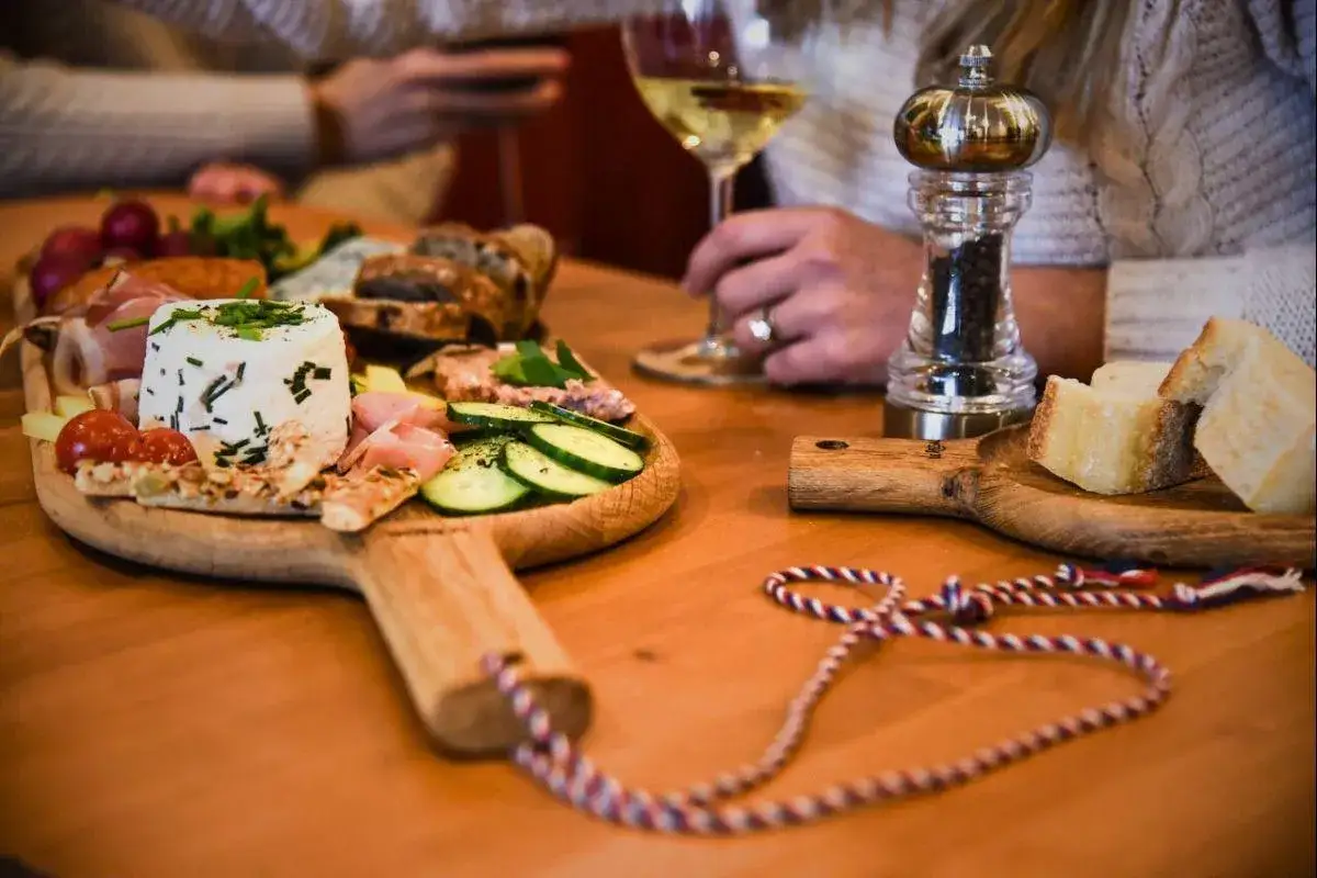 Un délicieux apéritif à base de vin, avec un plateau de fromages, charcuteries, crudités et pain. Parfait pour partager un moment convivial.